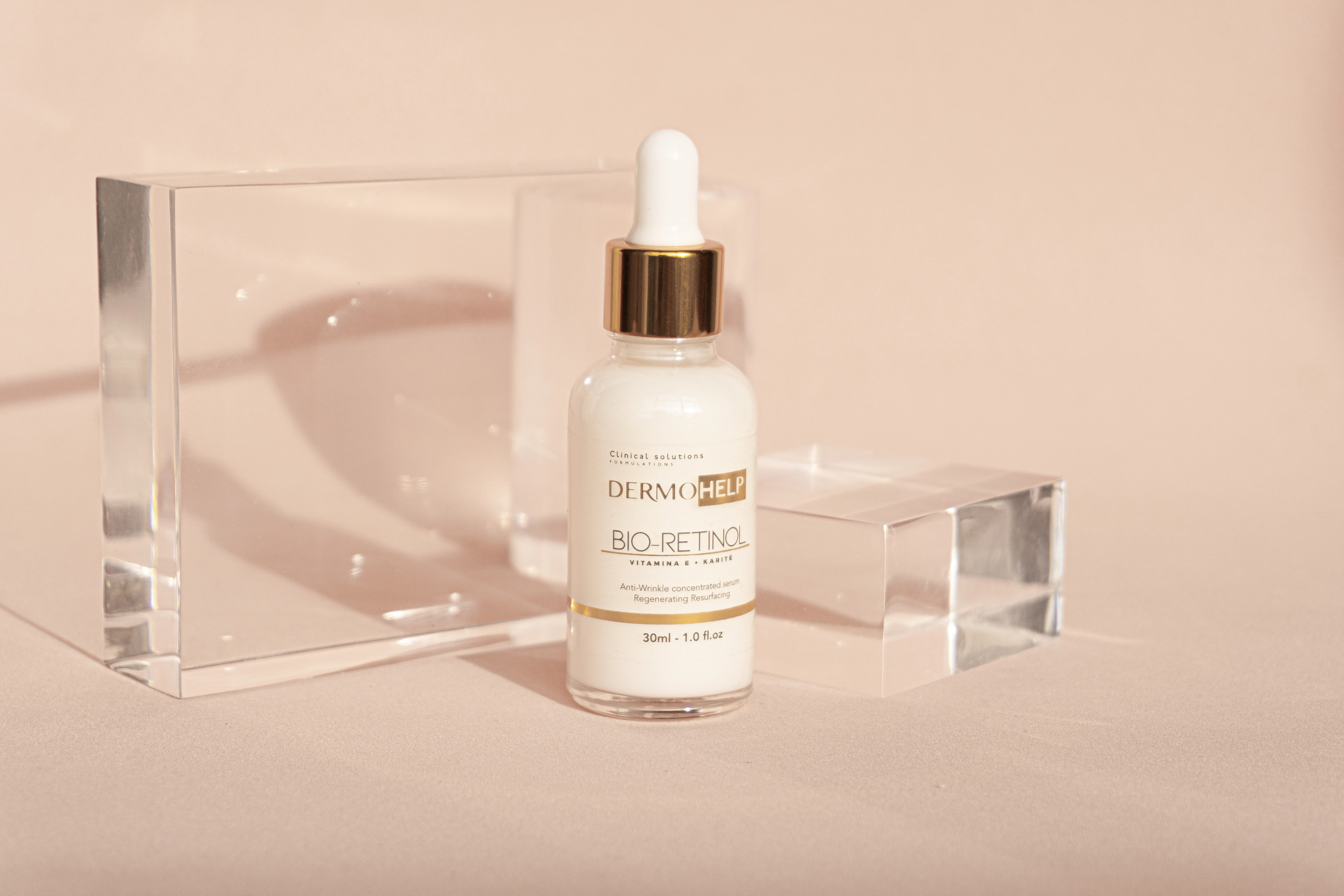 Sérum facial Bio-Retinol DERMOHELP en frasco de vidrio con gotero dorado, entre bloques acrílicos.