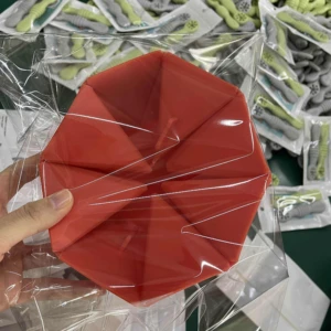 Crispetera roja en silicona plegable para hacer palomitas, rodeada de empaques de cucharas para bebé.