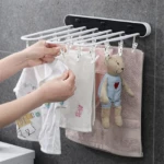 Tendedero plegable blanco con 5 barras y 10 pinzas, secando ropa de bebé y toalla.
