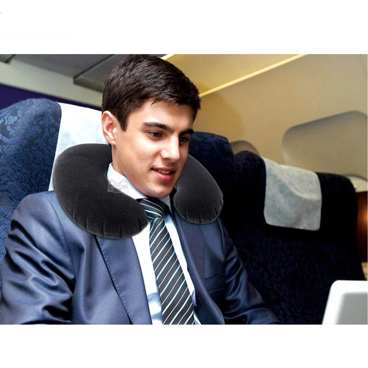 Hombre con traje y cojín de viaje cervical negro inflable en avión.