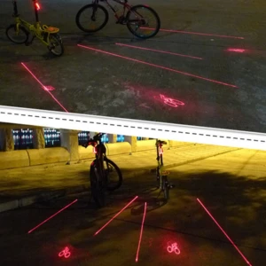 Luces traseras para bicicleta proyectan siluetas rojas de ciclista en el asfalto.