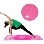 Tapete de yoga rosa vibrante con diseño floral, una mujer realiza postura de guerrero en él. Detalle de textura antideslizante.