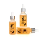 Serum 10 Vitamina C, tres frascos goteros ámbar con etiqueta naranja y blanca, uno de pie y dos recostados.