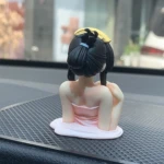 Figura miniatura de bailarina estilo anime, con vestido rosa, sentada, vista desde atrás.