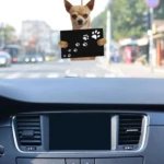 Adorno colgante de perro chihuahua con huellas en tablero de automóvil.