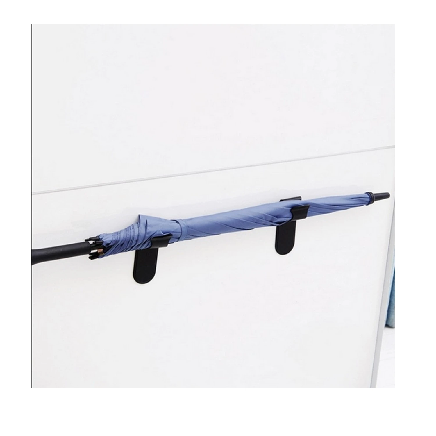 Gancho negro soporte universal para sombrilla azul colgada en pared blanca.