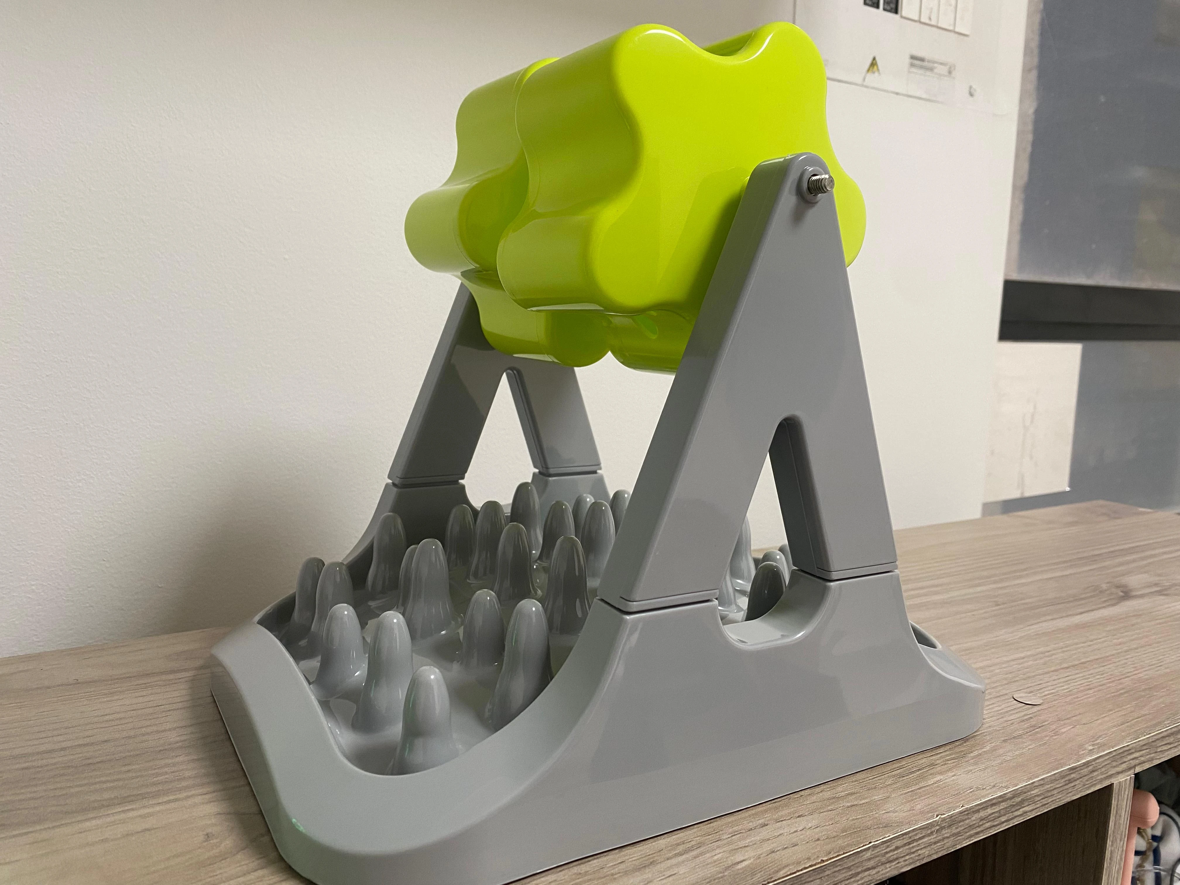 Comedero interactivo para mascotas de rodillo verde con base gris texturizada para ralentizar la alimentación.