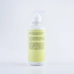 Botella cilíndrica de crema para peinar con dispensador de bomba, etiqueta amarilla con instrucciones, advertencias y lista de ingredientes en español.