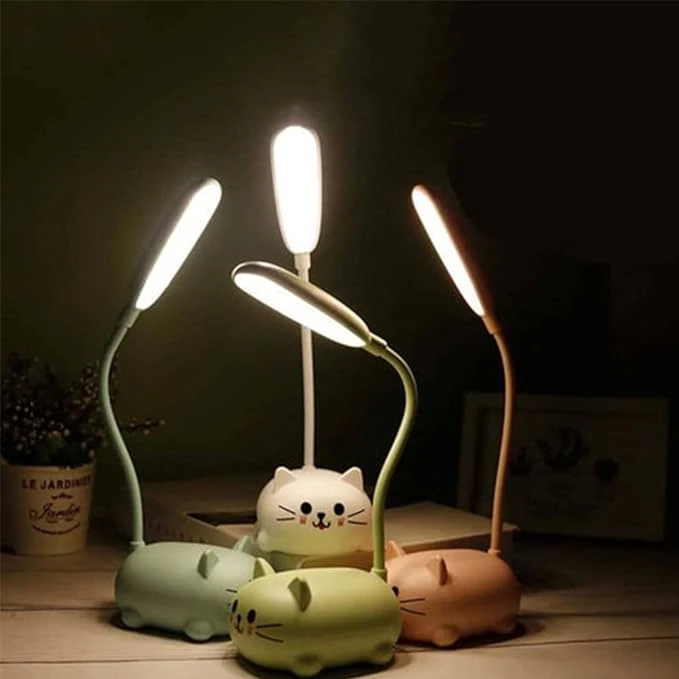 Cuatro mini lámparas de escritorio LED con diseño de gato, colores pastel, cuello flexible y luz blanca encendidas sobre una mesa en ambiente oscuro.