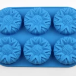 Molde de silicona azul para repostería con seis cavidades en forma de girasol, ideal para hornear o moldear postres con relieve detallado.