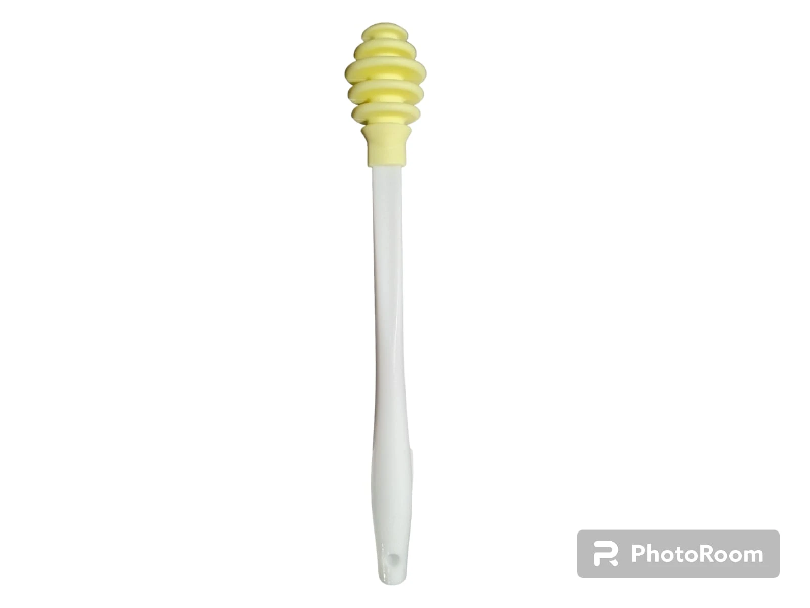 Cuchara para miel de silicona con cabeza estriada color amarillo y mango largo blanco, diseño ergonómico con orificio para colgar en el extremo inferior.