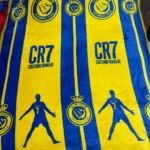 Cobija deportiva azul y amarilla de CR7 con silueta de jugador y logos de club.