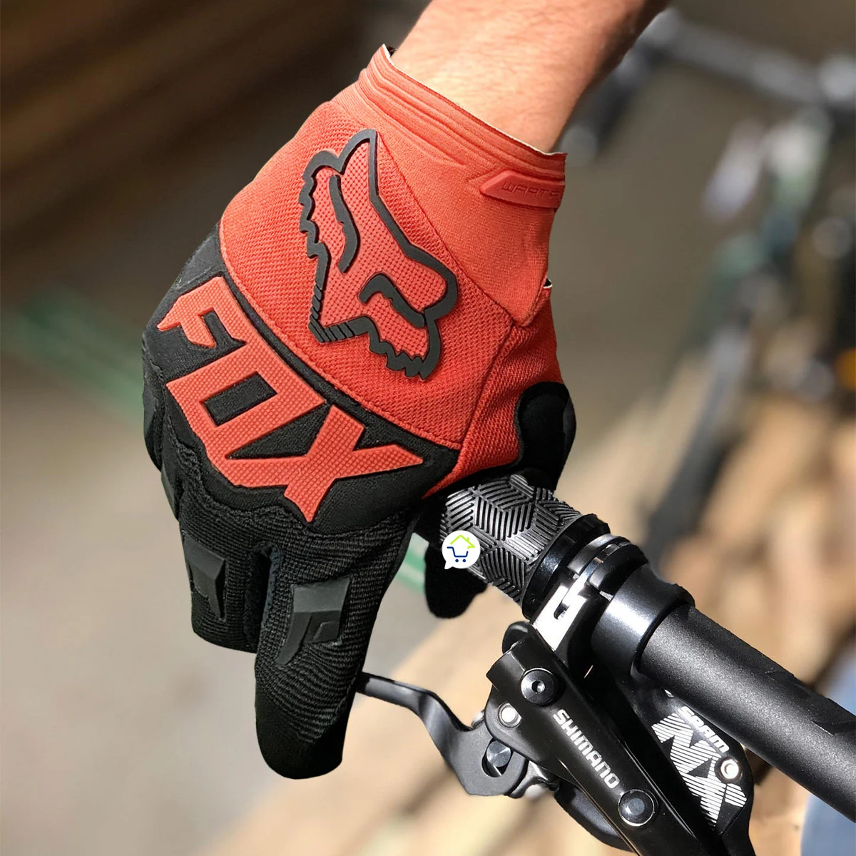 Guantes Fox naranjas de ciclismo para moto, con logo visible, sujetando manillar.