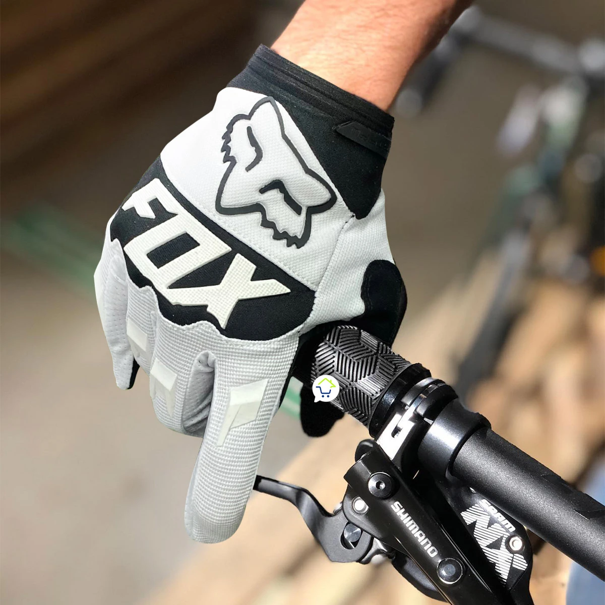 Guantes Fox blancos y negros para ciclismo, mano en manillar de bicicleta con freno Shimano.