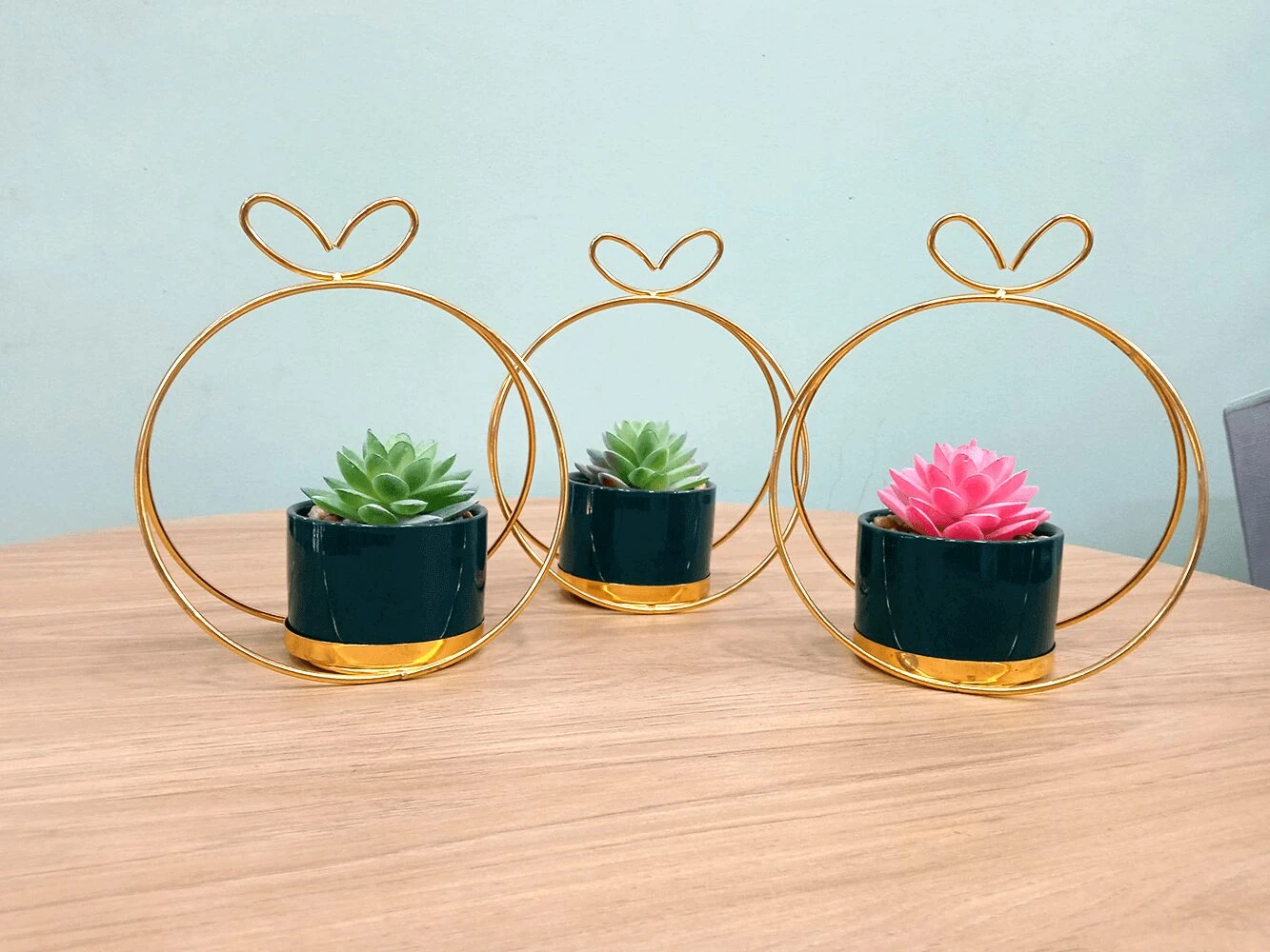 Trío de suculentas artificiales en macetas verde oscuro con soporte dorado, ideal para decorar.