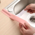 Cinta selladora adhesiva impermeable rosada para bordes de lavaplatos, mostrando instalación.