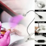 Lámpara UV LED para uñas con brazo flexible metálico, base de clip, cable USB y botón de encendido; muestra detalle del lente y su uso en manicura.