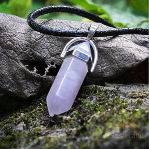 Colgante cuarzo rosa hexagonal con cordón negro sobre tronco cubierto de musgo.
