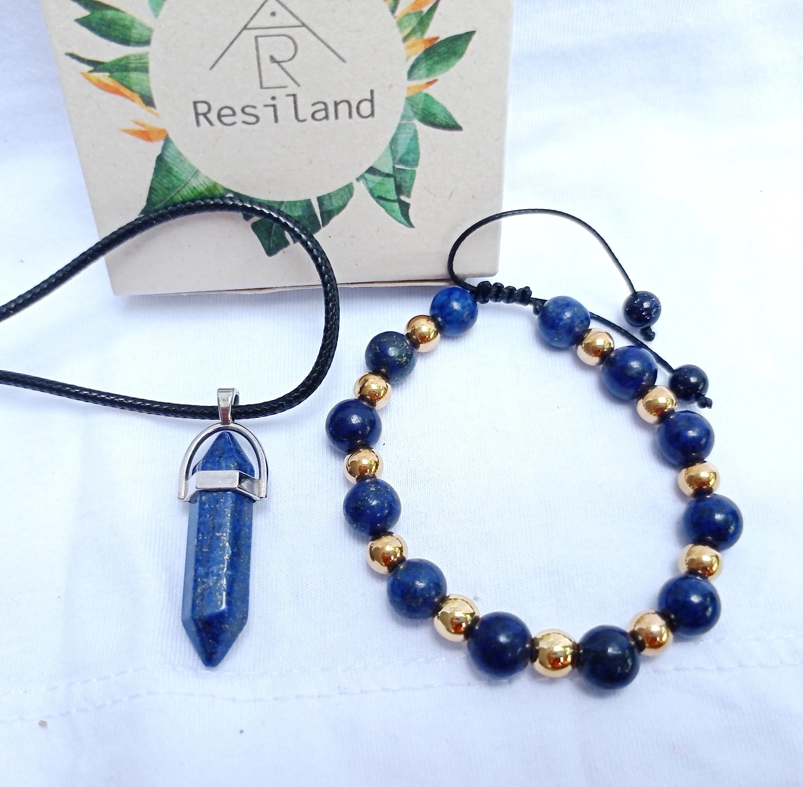 Combo de lapislázuli: colgante de cristal hexagonal y pulsera de cuentas azules y doradas sobre fondo blanco.