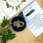 Orgonita Lluvia de Plata con mano de Fátima dorada, en base oscura y texto de Resiland.