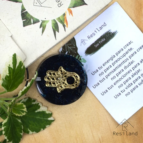 Orgonita Lluvia de Plata con mano de Fátima dorada, en base oscura y texto de Resiland.