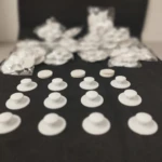Docena de ganchos adhesivos blancos para colgar con base circular y botón.