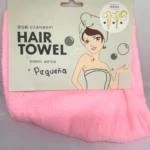 Toalla para cabello color rosa en tela de microfibra texturizada, presentada en empaque de cartón con instrucciones gráficas de uso y nombre Pequeña.