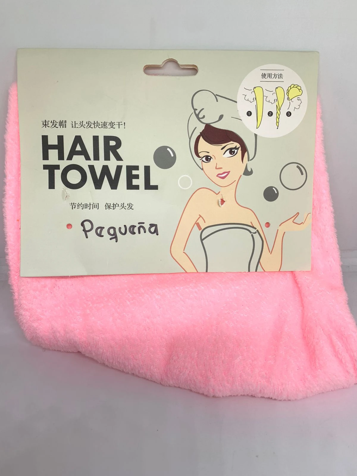 Toalla para cabello color rosa en tela de microfibra texturizada, presentada en empaque de cartón con instrucciones gráficas de uso y nombre Pequeña.