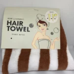 Toalla de microfibra para secar el cabello con estampado de rayas café y blancas, empacada con cartón informativo que ilustra paso a paso su uso.