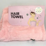 Toalla de microfibra color rosa para el cabello, con empaque que muestra instrucciones gráficas de uso y una de mujer con el producto puesto.