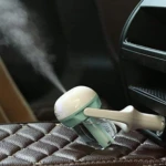 Humidificador ambientador para carro, blanco y verde, emitiendo vapor sobre asiento de cuero.