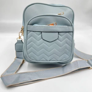 Bolso manos libres mujer azul pálido con diseño capitonado en zigzag y correa ajustable.