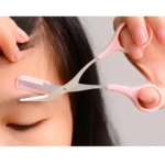 Tijeras rosadas para perfilar cejas con peineta integrada, cortando vellos de la ceja izquierda de persona.