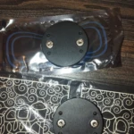 Tapete masajeador corporal y mariposa de electrodos negros con conectores plateados.