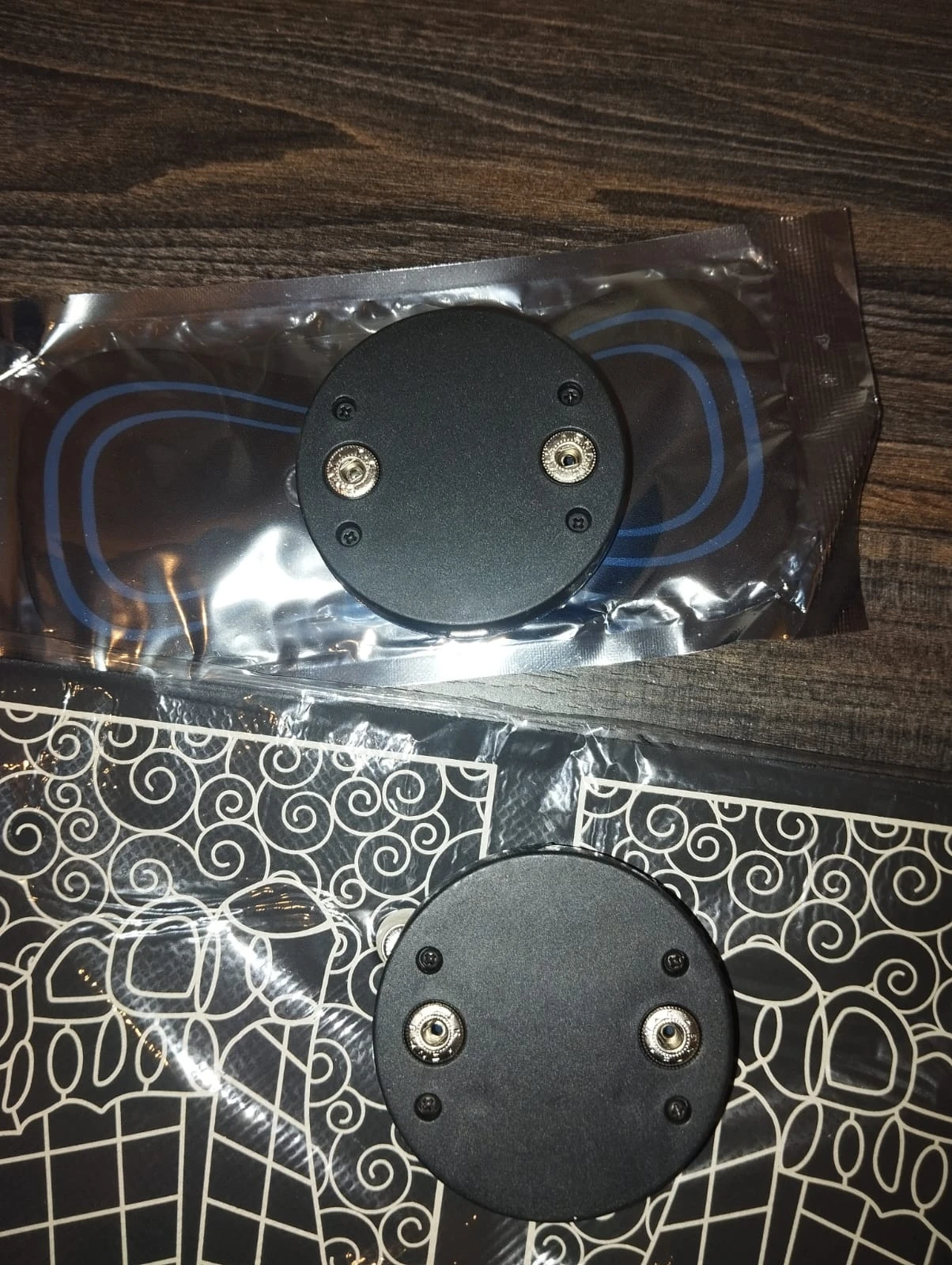 Tapete masajeador corporal y mariposa de electrodos negros con conectores plateados.