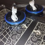 Combo Tapete Masajeador y Mariposa Masaj: dos dispositivos circulares negros con bordes azules y cables blancos USB conectados.