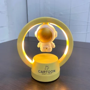 Lámpara de noche LED amarilla con astronauta flotante, diseño moderno para mesita.