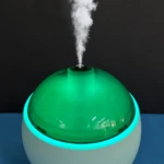 Humidificador Q803 blanco con cúpula verde translúcida y luz led azul emitiendo vapor.