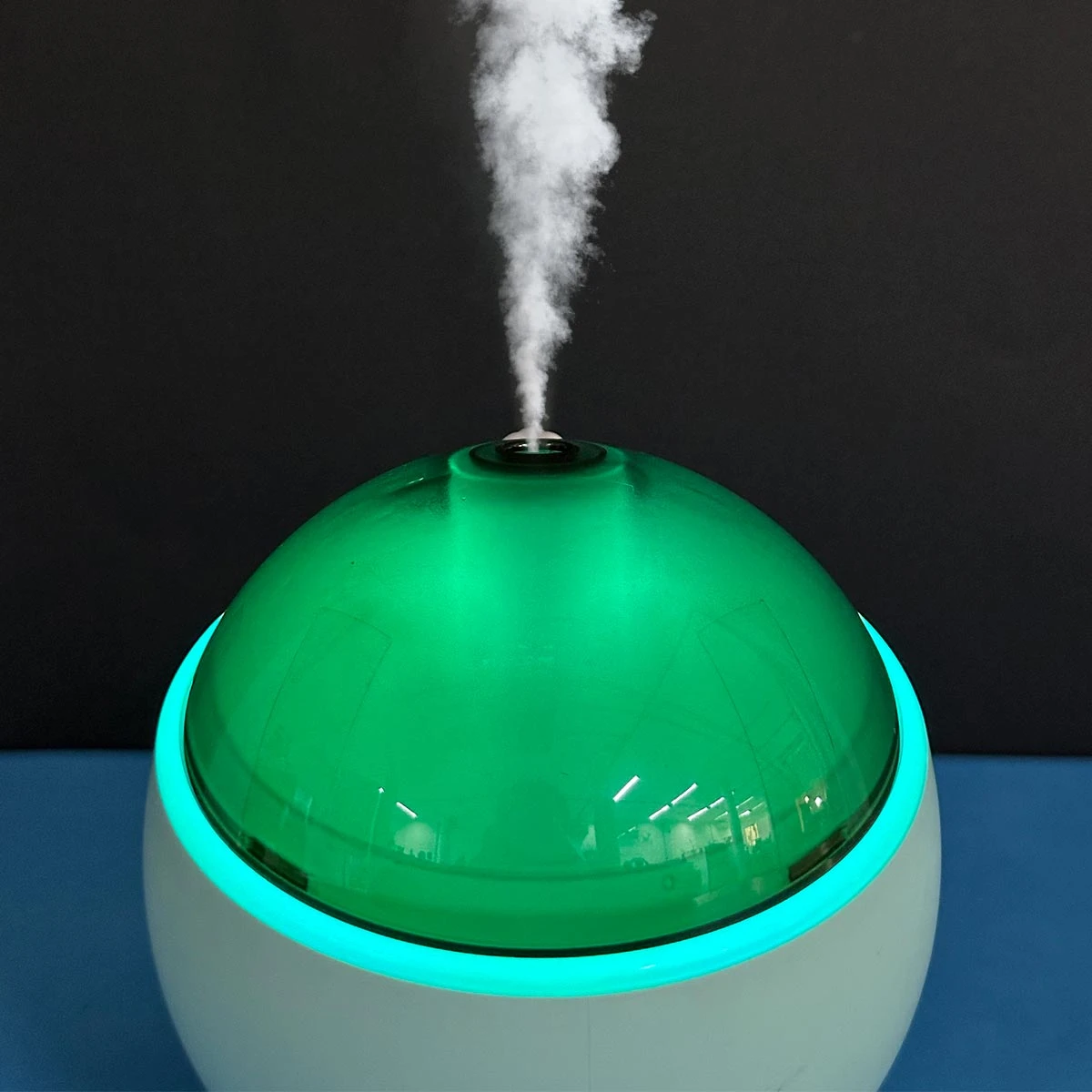 Humidificador Q803 blanco con cúpula verde translúcida y luz led azul emitiendo vapor.
