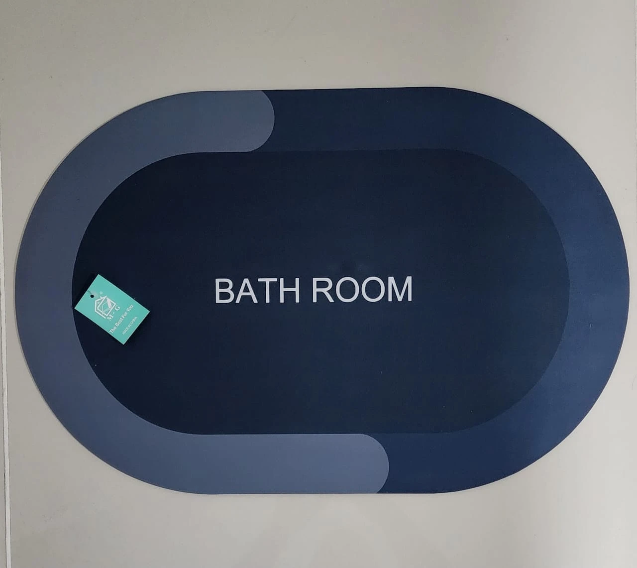 Tapete antideslizante ovalado azul oscuro para baño, con diseño moderno y etiqueta.