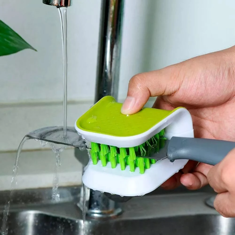 Cepillo lava loza con cerdas verdes y base blanca para limpiar cuchillos bajo el grifo.