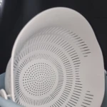 Colador blanco de plástico con múltiples orificios y escurridor giratorio incorporado, apto para lavar frutas y verduras.