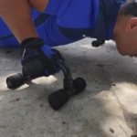 Soporte para push up negro con agarres ergonómicos azules, utilizado por persona con guantes para ejercicio.