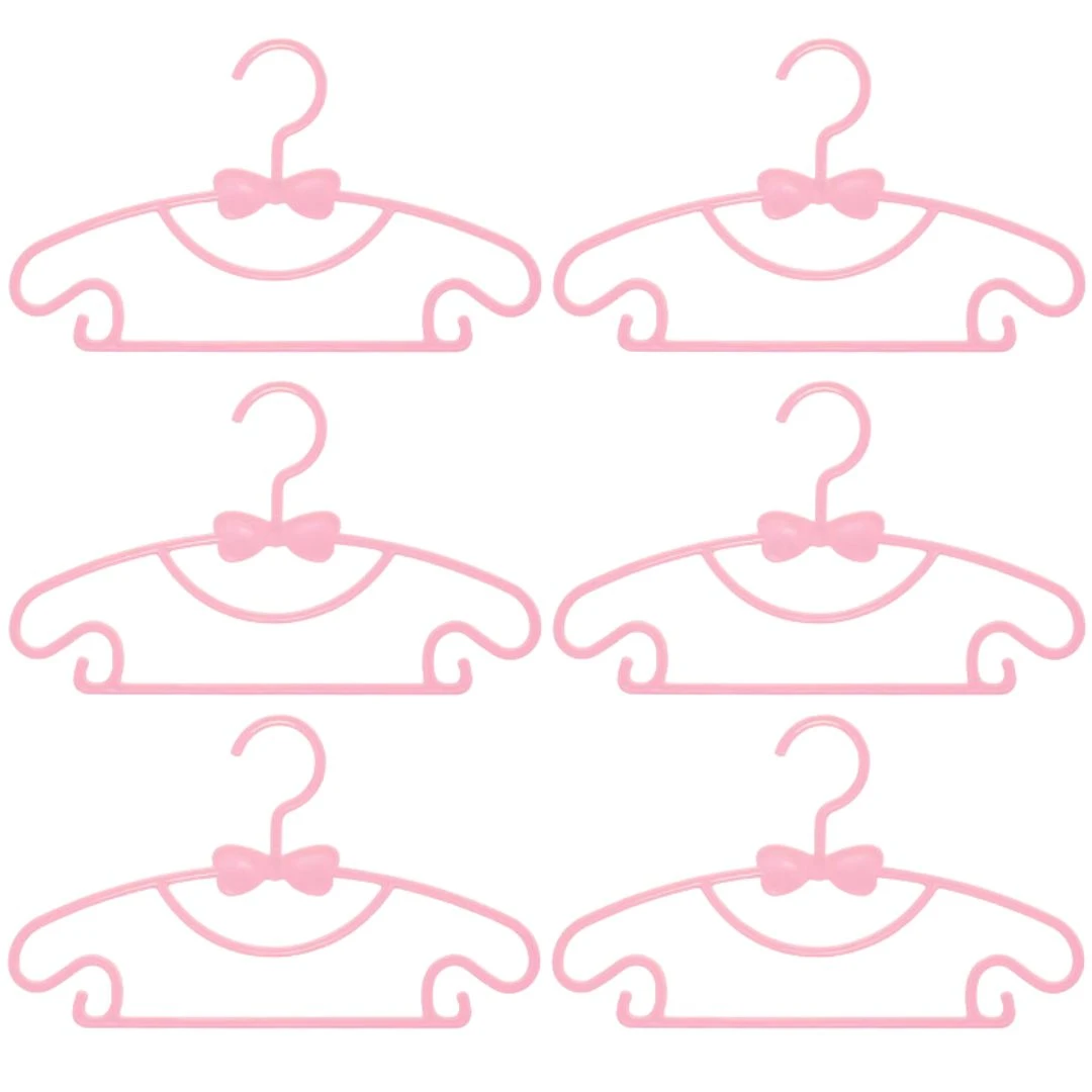 Kit 6 ganchos flexibles rosa para ropa de bebé, con forma de carita y detalles de moño, ideales para secar y organizar.