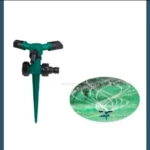 Aspersor de agua verde con 3 boquillas y base con pica, junto a otro en funcionamiento regando césped.
