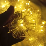 Cortina de luces LED navideñas con 3 metros de flores transparentes tipo campana, tono cálido.