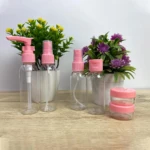 Set de 6 envases transparentes para viajes con tapas rosas, incluye dos frascos pequeños apilados.