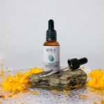Sérum despigmentante facial con boerhavia diffusa en frasco ámbar con gotero, rodeado de flores amarillas.