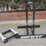 Rodillos traseros para bicicleta Giant y Trinity, negros, con soporte y rodillos metálicos en exterior de ladrillo.