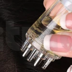 Aplicador manual transparente para cuero cabelludo con puntas metálicas dosificadoras y escala de medición de 1 a 3 ml visible en el cuerpo del recipiente.